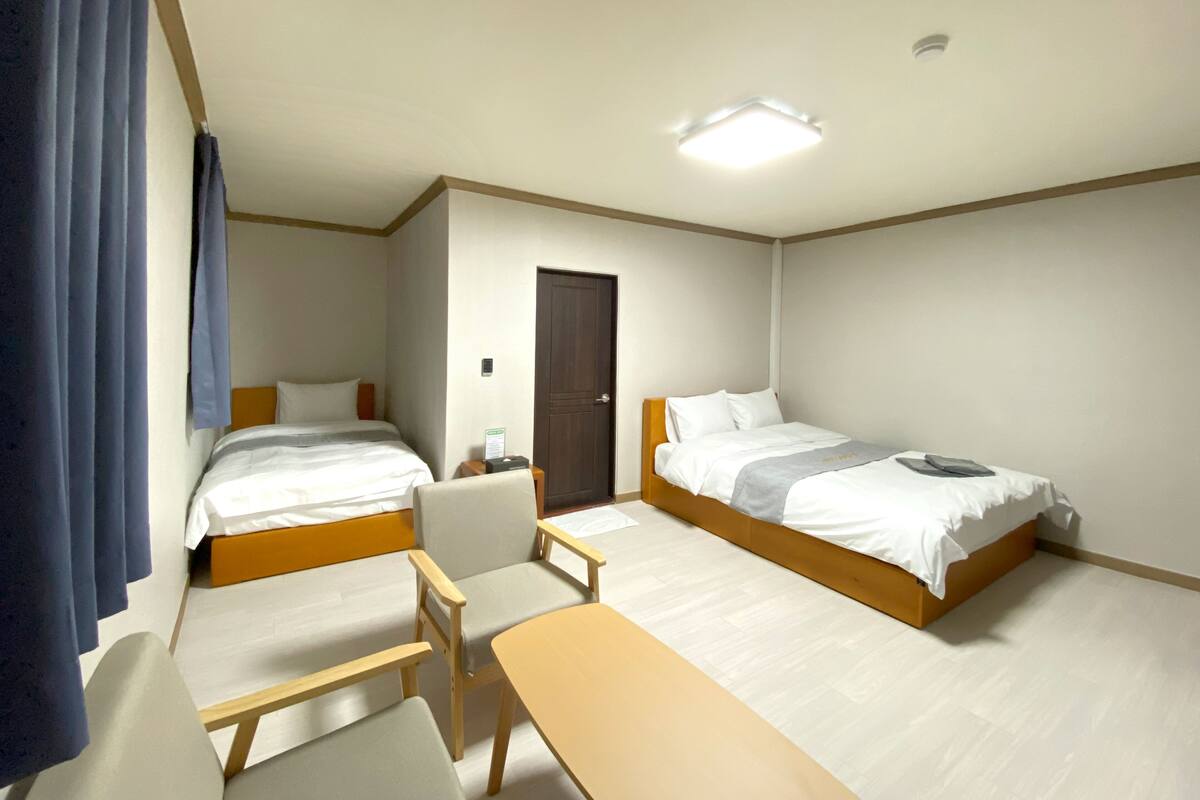 A hotel room with two beds, a desk, and a chair.
