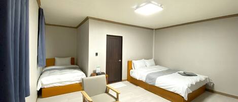 A hotel room with two beds, a desk, and a chair.