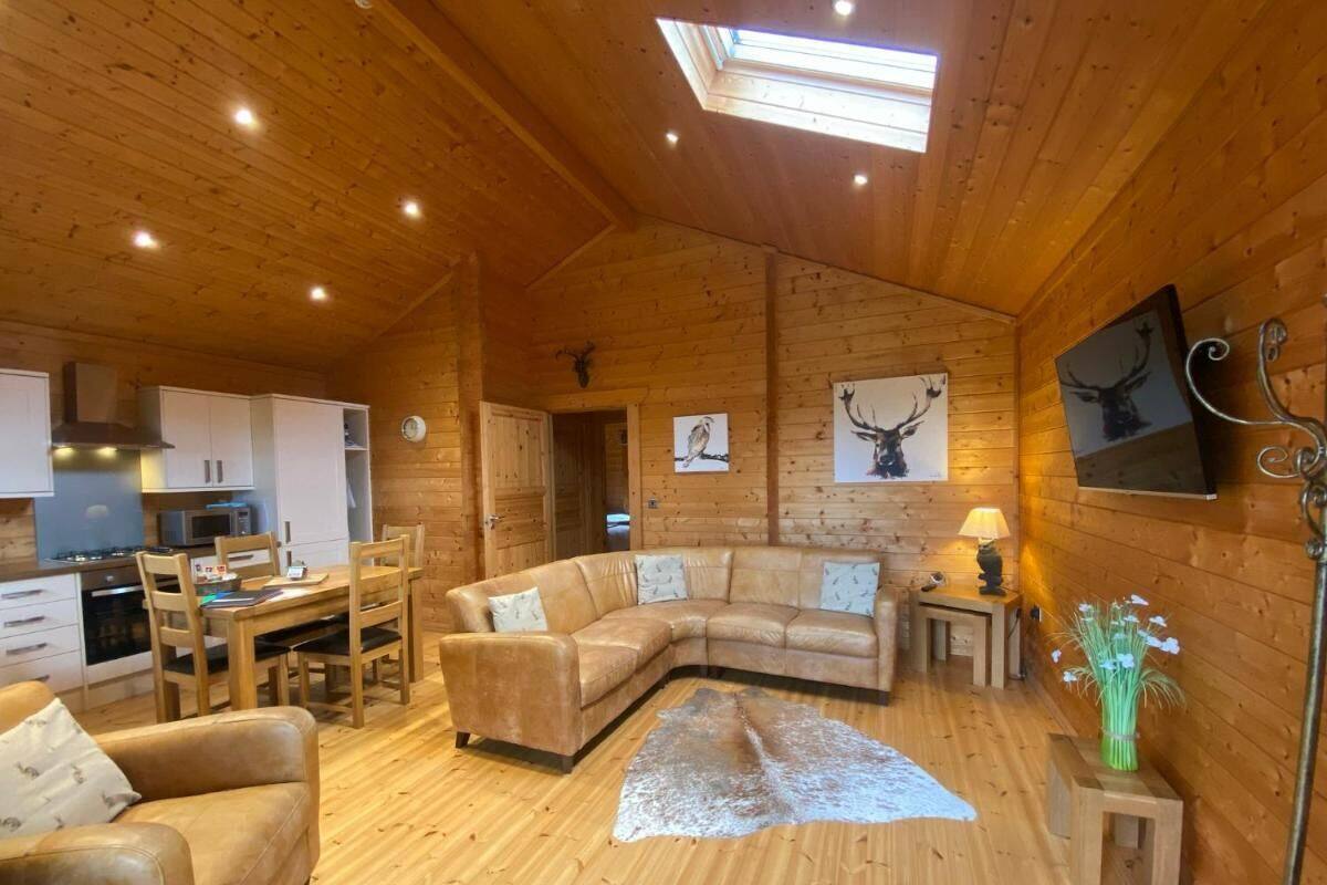 A cozy cabin interior with a wooden interior, a dining area, a sofa, and a fireplace.