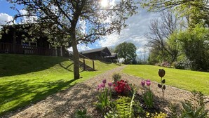 A well-maintained garden with a variety of flowers and a wooden fence leading to a building. - Hollybush Lodges (Radstock)