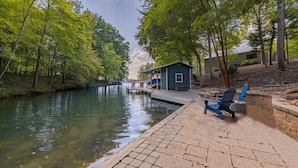 Una cabaña junto al lago con un muelle que se adentra en el agua, rodeada de árboles.