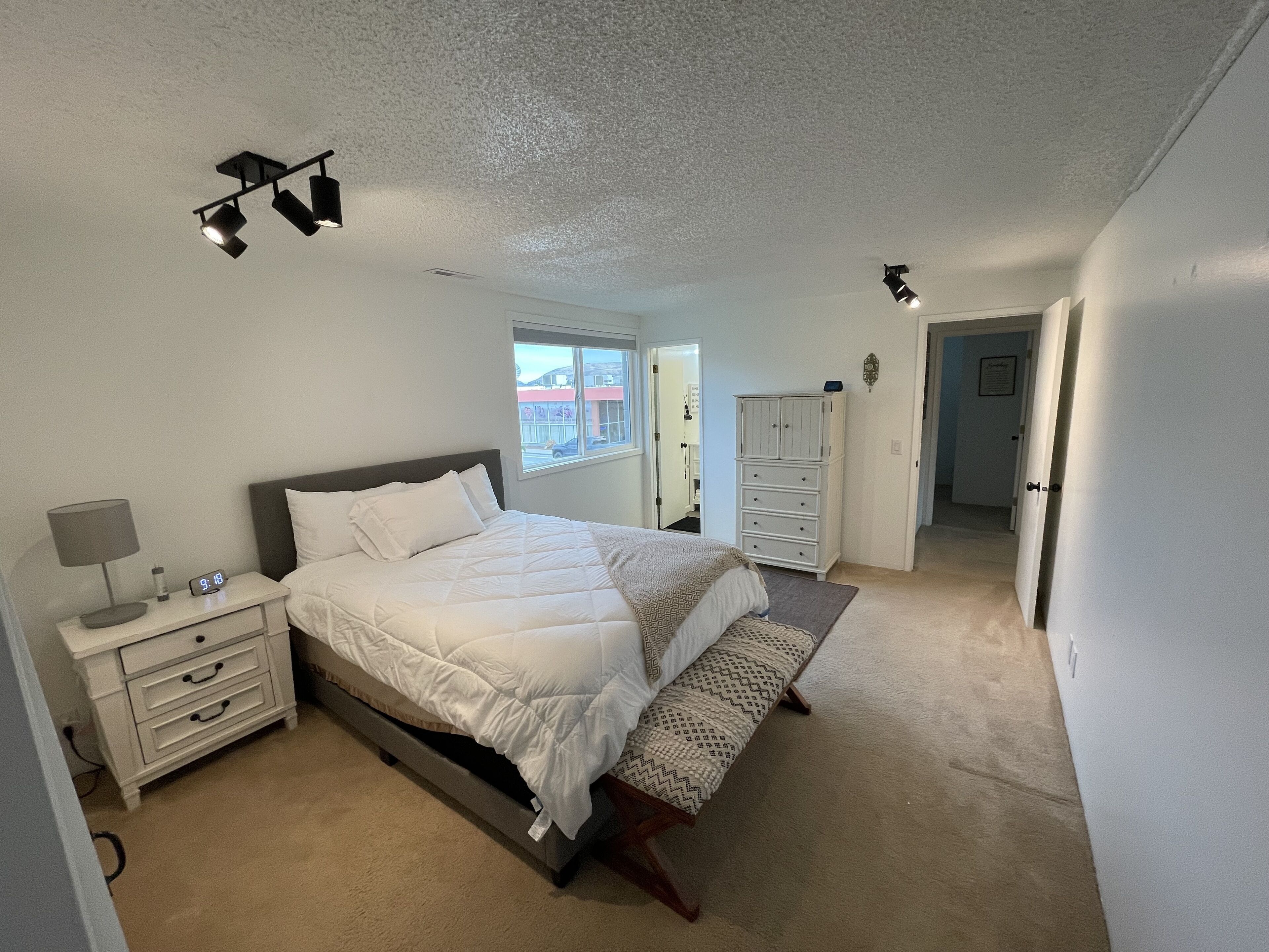 Una camera da letto con un letto, un comodino, una lampada e una finestra.