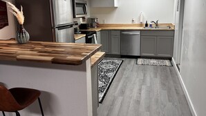 A modern kitchen with grey cabinets, a stainless steel refrigerator, a microwave, and a wooden countertop. - 3 bedroom loft (Wenatchee)