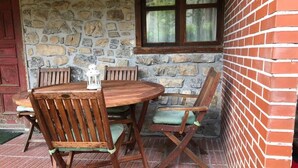 A stone wall with a wooden table and chairs, a window, and a red brick wall.