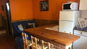 A compact kitchen with a wooden table and chairs, a microwave, and a refrigerator.
