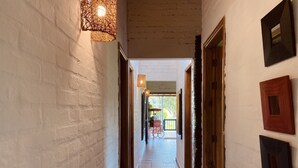 A corridor with white brick walls, wooden doors, and hanging wicker lamps. - Family Farm!Wi-Fi,Kiosk,Pool & Mountain Views. (Puerto Samaria)