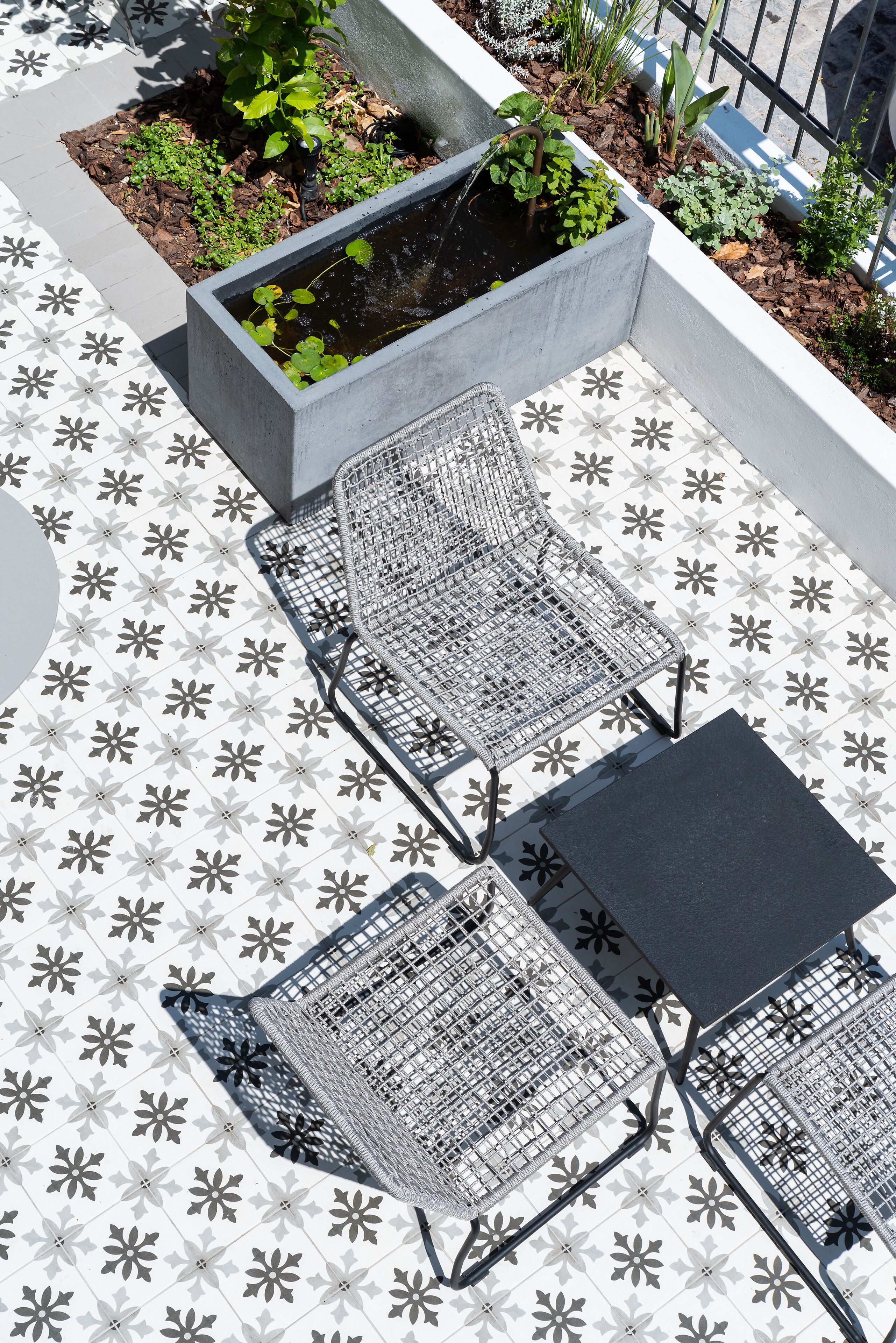 A patio with a patterned tile floor, two metal chairs, and a small table.