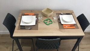 Een eettafel gedekt met borden, bestek en glazen, omringd door zwarte stoelen.