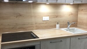 Een moderne keuken met een roestvrijstalen afzuigkap, een dubbele spoelbak en een ingebouwde oven.