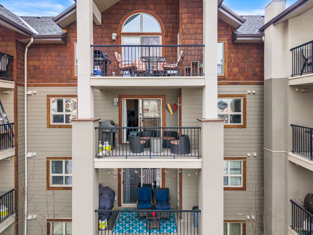 Un immeuble résidentiel à plusieurs étages, doté de balcons, d’un espace extérieur aménagé et d’une piscine visible.