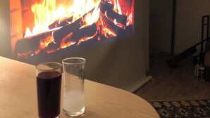 Una habitación con chimenea, una mesa con dos vasos y una alfombra estampada.