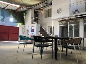 Un'area esterna coperta con tavolo e sedie, una scala e un cancello rosso.