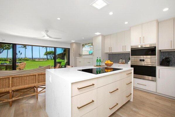 A modern kitchen with a large island, built-in appliances, and a view of a lush garden. - Maalaea Surf | Oceanfront 1 BR | Water Front | Car Incl. w/ 6+ Nights | MSR-F2 by KBM (Kihei)