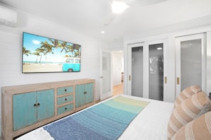 A bedroom with a bed, a TV on the wall, a wardrobe, and a door.