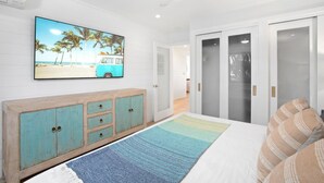 A bedroom with a bed, a TV on the wall, a wardrobe, and a door.