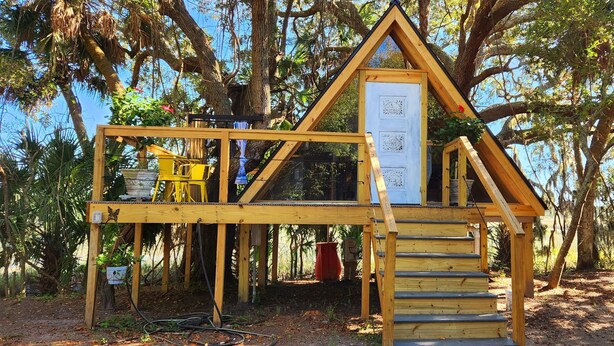 A wooden structure with a triangular roof, a staircase, and a door.