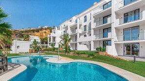 A modern apartment building with a swimming pool, surrounded by greenery and a hillside view. - Paloma Beach apartment 5.1a (Manilva)