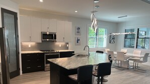 A modern kitchen with a central island, stainless steel appliances, and a dining area with bar stools.
