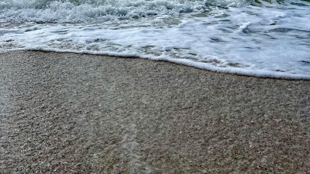 A beach with waves and a clear sky.