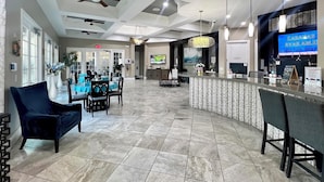 A spacious lobby with a reception desk, seating area, and a television displaying 'CABANAS AVAILABLE.' - EPIC VALUE! Private Pool Oasis! Water Slide! Close 2 Disney! 5488 (Davenport)