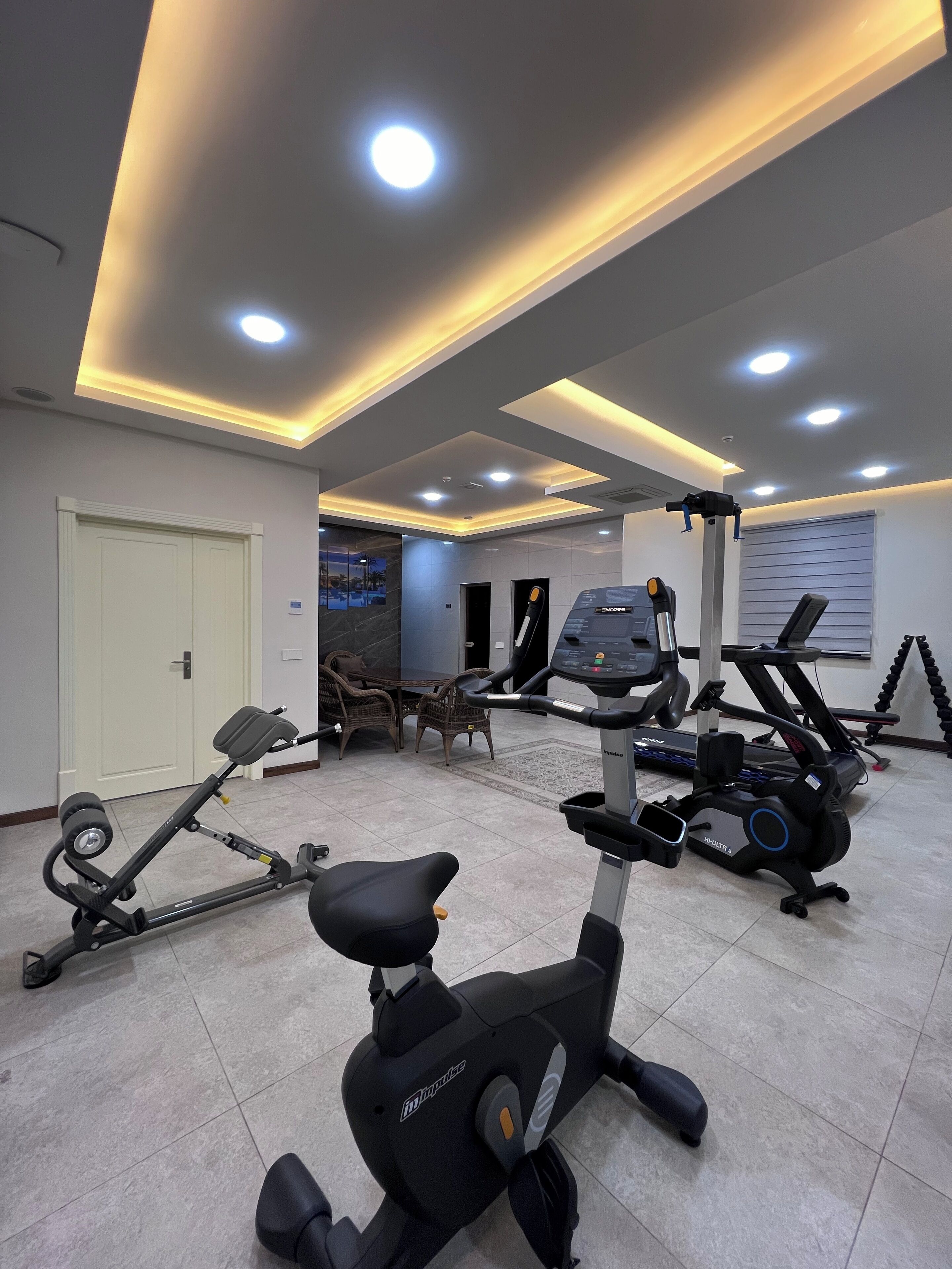 Een sportschool met fitnessapparatuur, waaronder loopbanden en een elliptische machine.