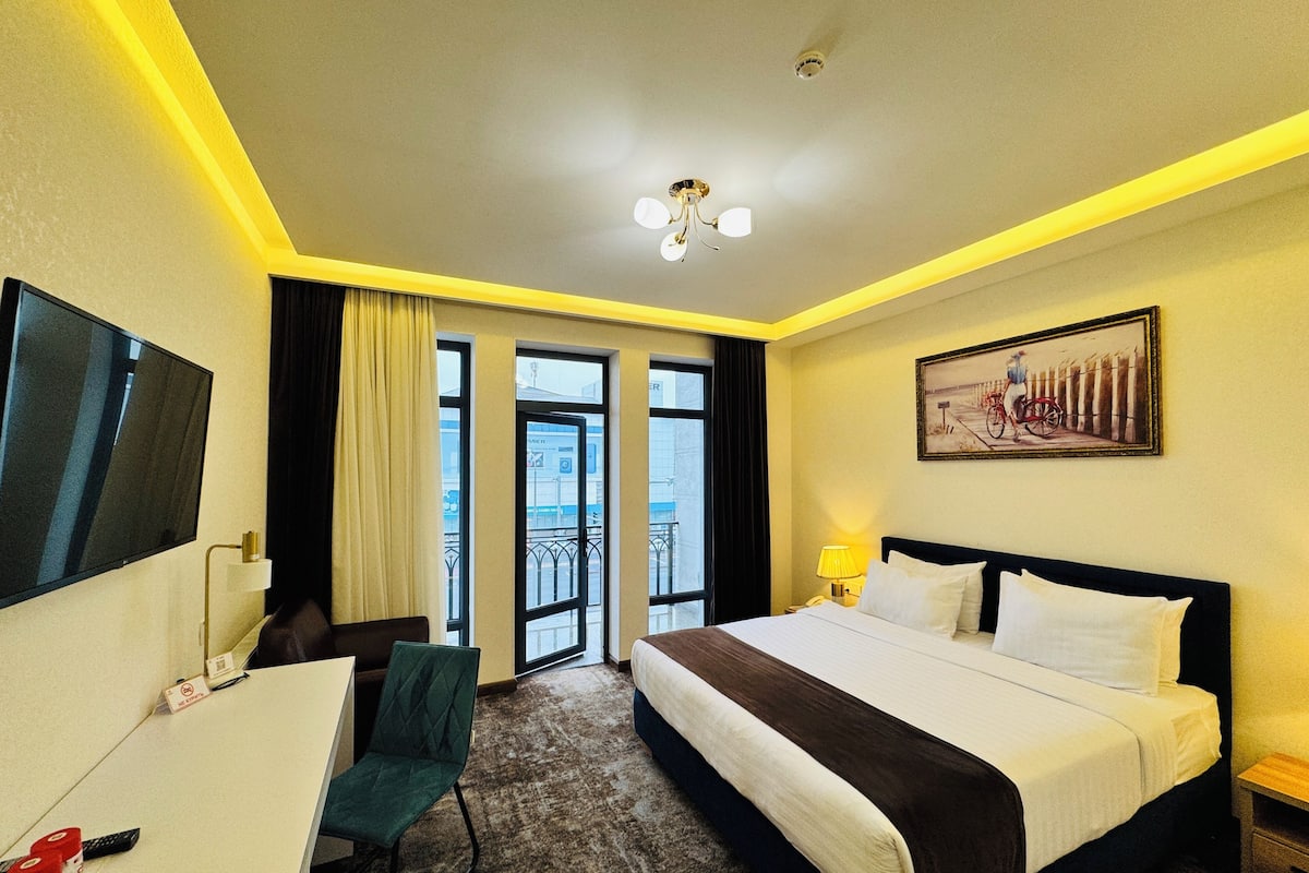 Une chambre d’hôtel avec un lit, un bureau, une chaise et un tableau au mur.