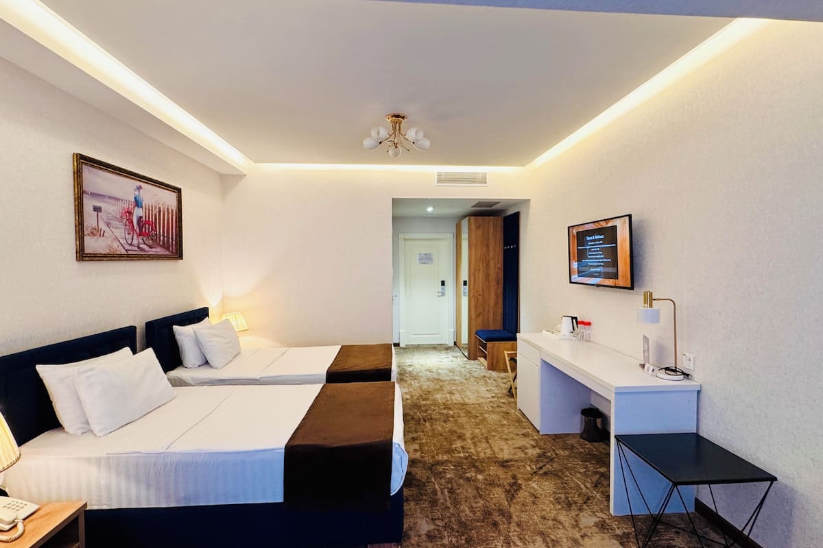 Une chambre d’hôtel avec un lit, une table de chevet, une lampe et un téléviseur fixé au mur.