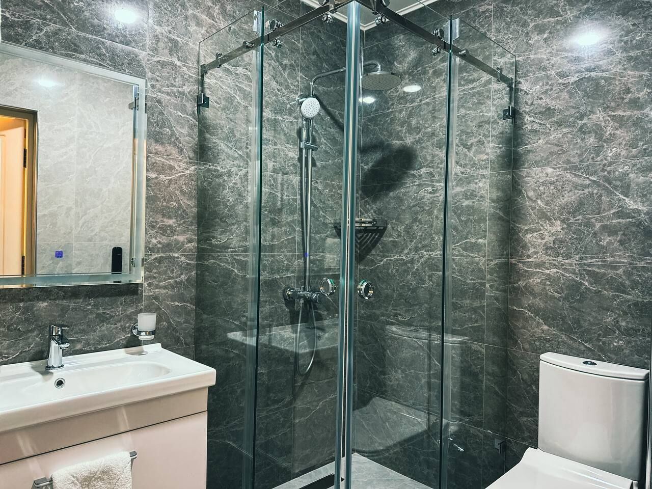 Un baño moderno con ducha de vidrio, lavamanos e inodoro.