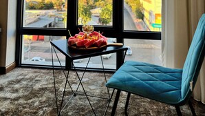 A room with a large window, a table with a dessert, and a blue chair. - Garnet Mir Hotel (Tashkent)
