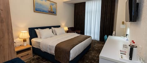 Une chambre d’hôtel avec un lit, des lampes de chevet, un tableau, une télévision et une salle de bain équipée d’un lavabo et d’un miroir.