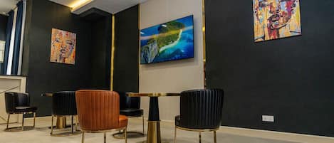 A modern room with a large TV, black and gold chairs, and abstract art on the walls.
