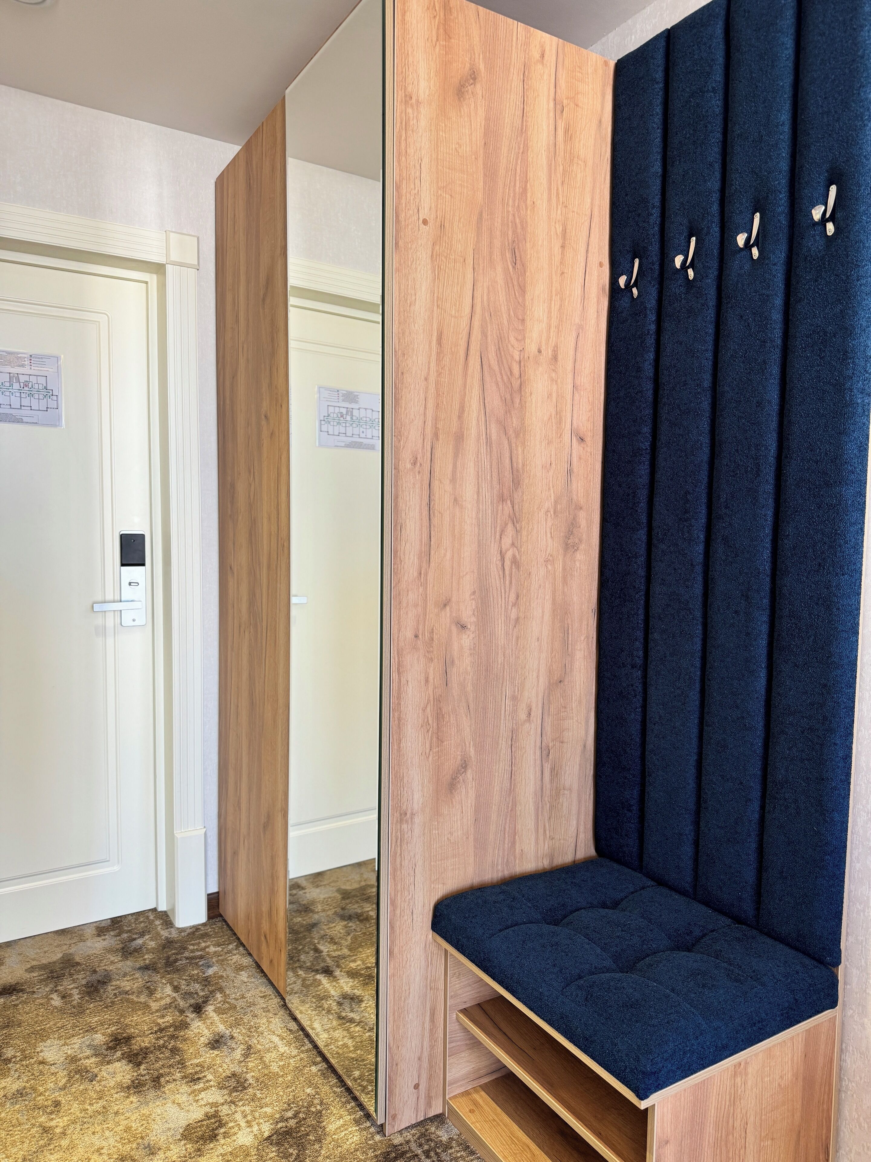 A room with a mirrored wardrobe, a bench, and a door with a lock.