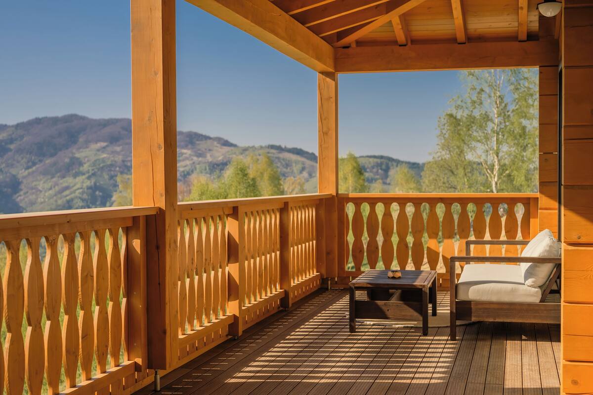 Une terrasse en bois avec une clôture en bois, un canapé et une table.