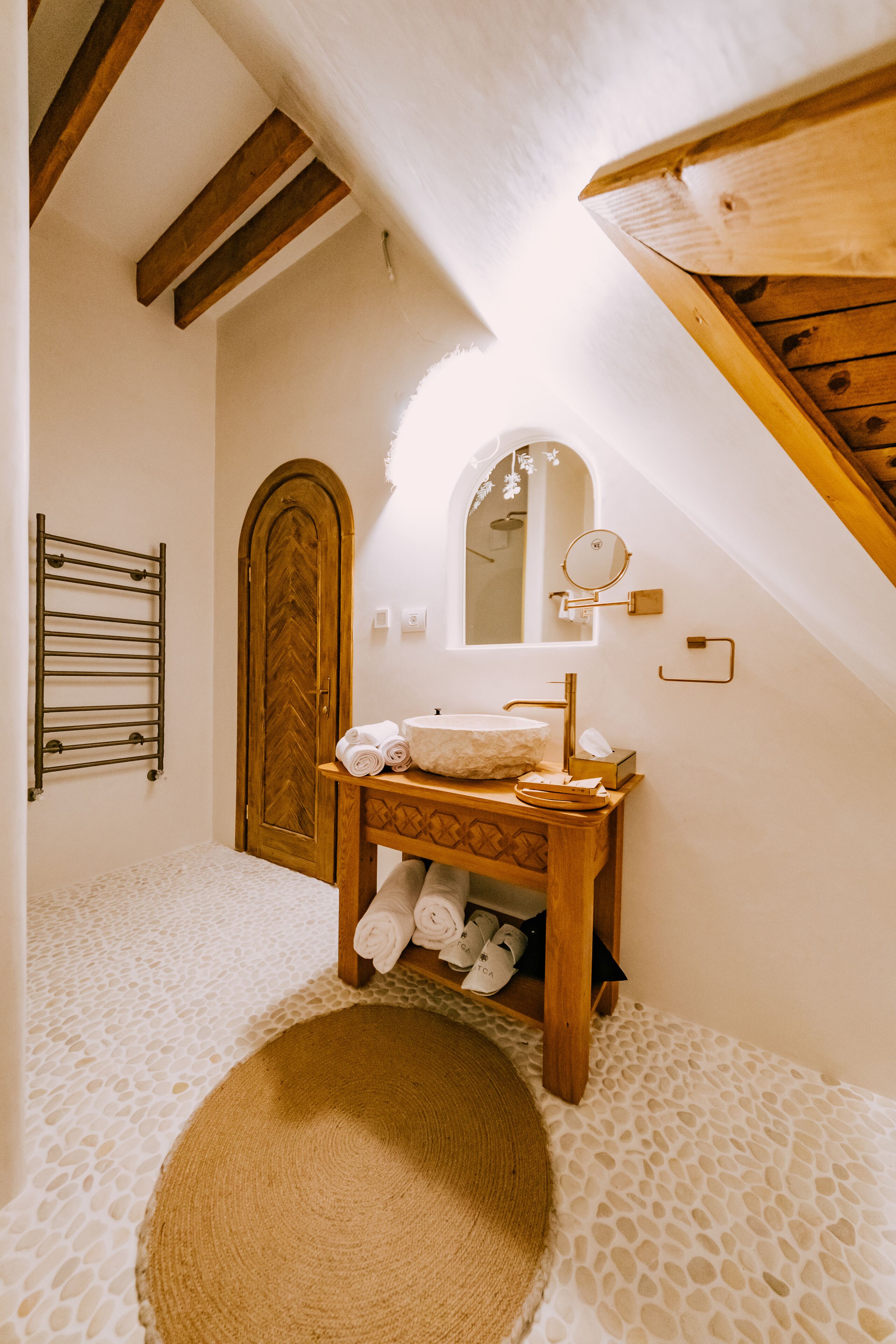 A bathroom with a wooden vanity, a towel rack, a mirror, and a patterned floor.