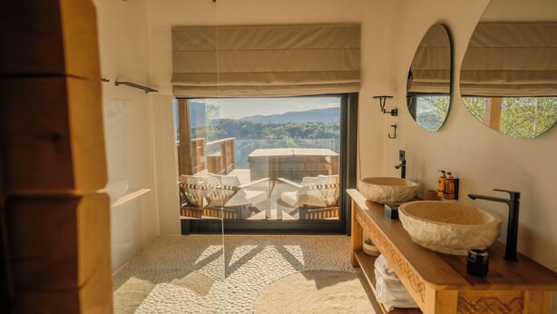 A bathroom with a large window, two sinks, and a wooden vanity.