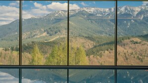 A view through a window of a mountain landscape with a lake reflecting the scenery.