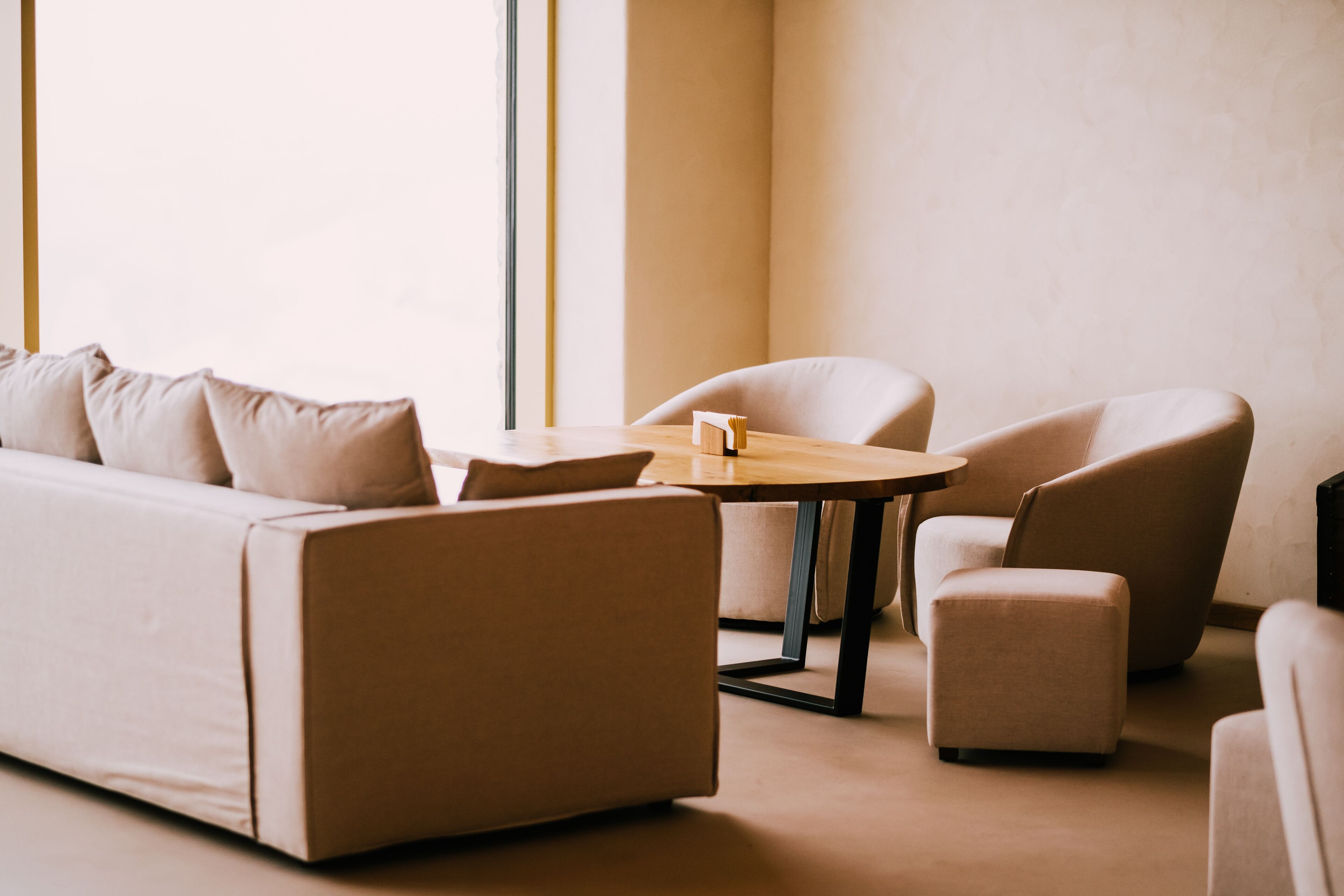 A modern living room with a sofa, two armchairs, a small ottoman, and a wooden coffee table.