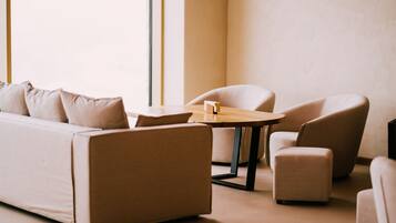 A modern living room with a sofa, two armchairs, a small ottoman, and a wooden coffee table.