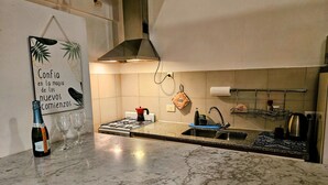 Een moderne keuken met een gasfornuis, een roestvrijstalen spoelbak en een spatwand.
