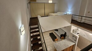 Een modern appartement met een trap, een bank, een eettafel en een keukenhoek.