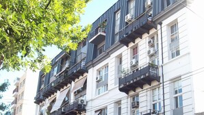 Een meerlaags gebouw met balkons, airconditioners en een boom ervoor.