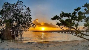 A beach scene with a sunset, a pier, and trees. - Peaceful & Private Waterfront Retreat w/Heated Pool near Beach & Downtown Stuart (Stuart)