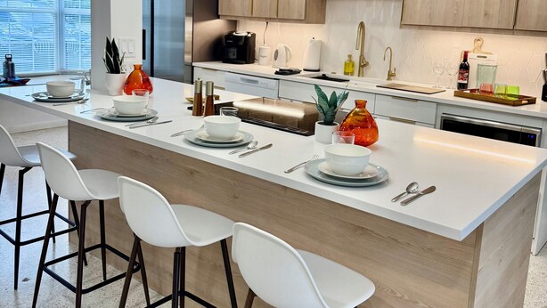 A modern kitchen with a central island, bar stools, wooden cabinets, and a pendant light. - Peaceful & Private Waterfront Retreat w/Heated Pool near Beach & Downtown Stuart (Stuart)