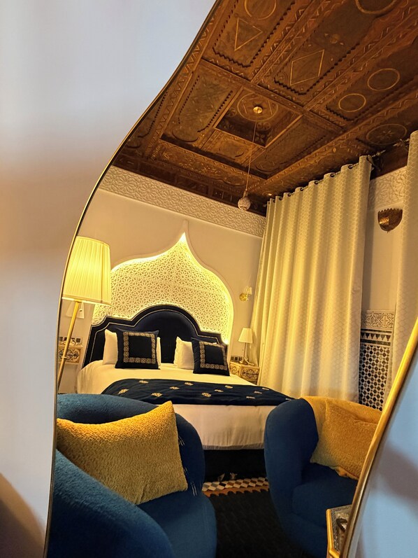 A hotel room with a large bed, two armchairs, a decorative ceiling, and a patterned wall. - Riad Fes Palais Bab Sahra & Cooking Workshops  (Fes)