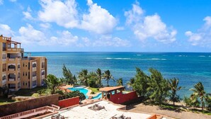 A resort with a pool, palm trees, and a view of the ocean.