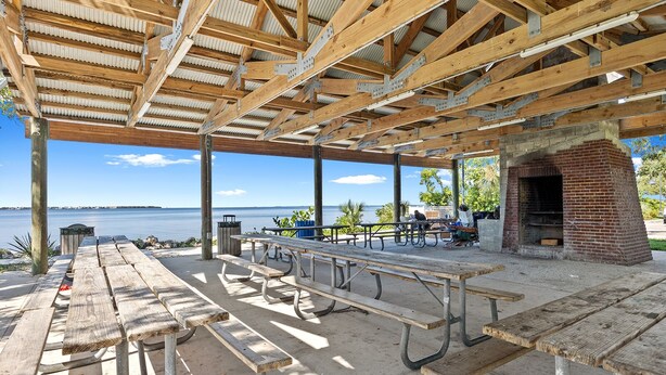An outdoor covered picnic area with wooden benches and a brick barbecue grill, overlooking a body of water. - Luxury place - 23019 in Port Charlotte , one block to the Bayfront Park/Harbor (Port Charlotte)