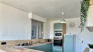 Une cuisine moderne avec des meubles de couleur bleu clair, un plan de travail en bois, un four encastré et un four à micro-ondes.