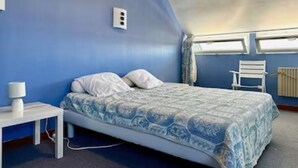 Une chambre avec un lit simple, une table de chevet, une chaise et une fenêtre.