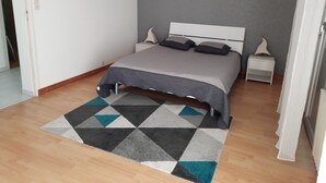 Une chambre à coucher avec un lit, des tables de chevet, un tapis à motifs et des appliques murales.
