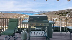 Une terrasse avec un fauteuil de jardin vert, un barbecue portable et une bouteille de propane.